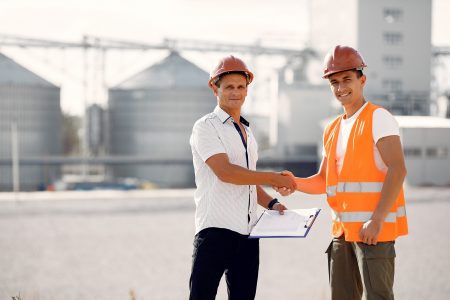 Engineers near the factory. Mtn in a helmet. Inspector looks at the building.